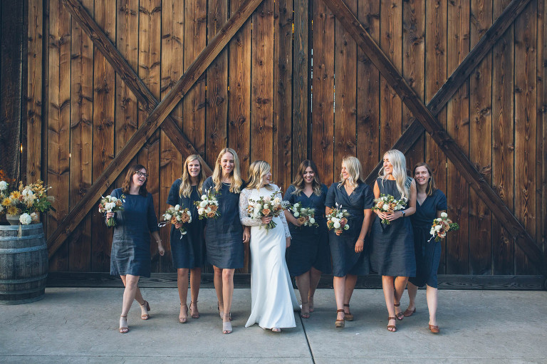 wedding party bridesmaids and bride walking in front of tin roof barn